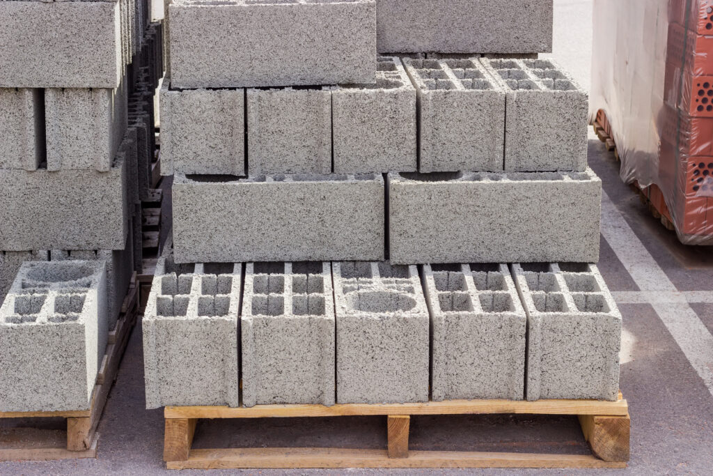 Perforated concrete masonry units on a wooden pallets among other building materials on an outdoor warehouse